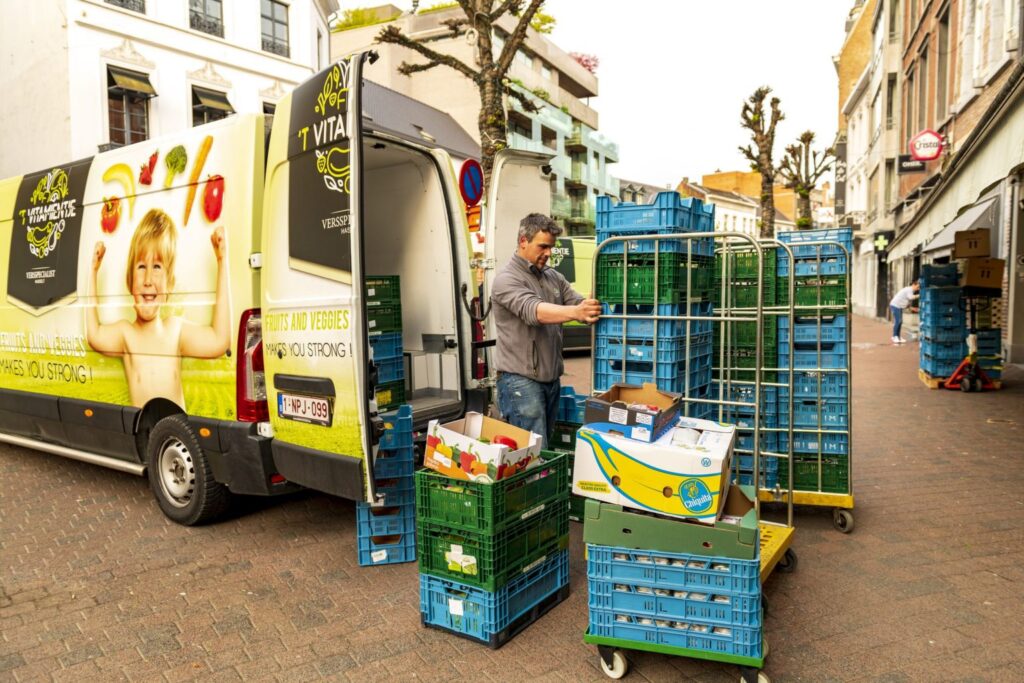 Medewerker van 't Vitamientje die de dagelijkse levering vers fruit en verse groenten uit de bestelwagen laadt.